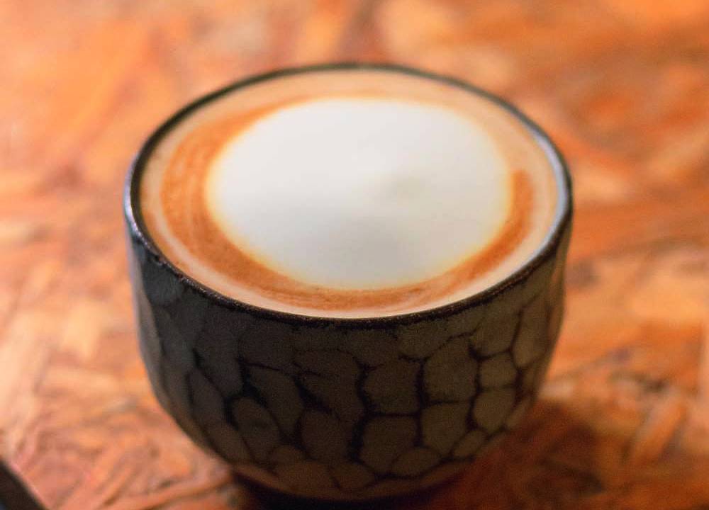 Xícara baixa de cerâmica com café servido com leite e espuma