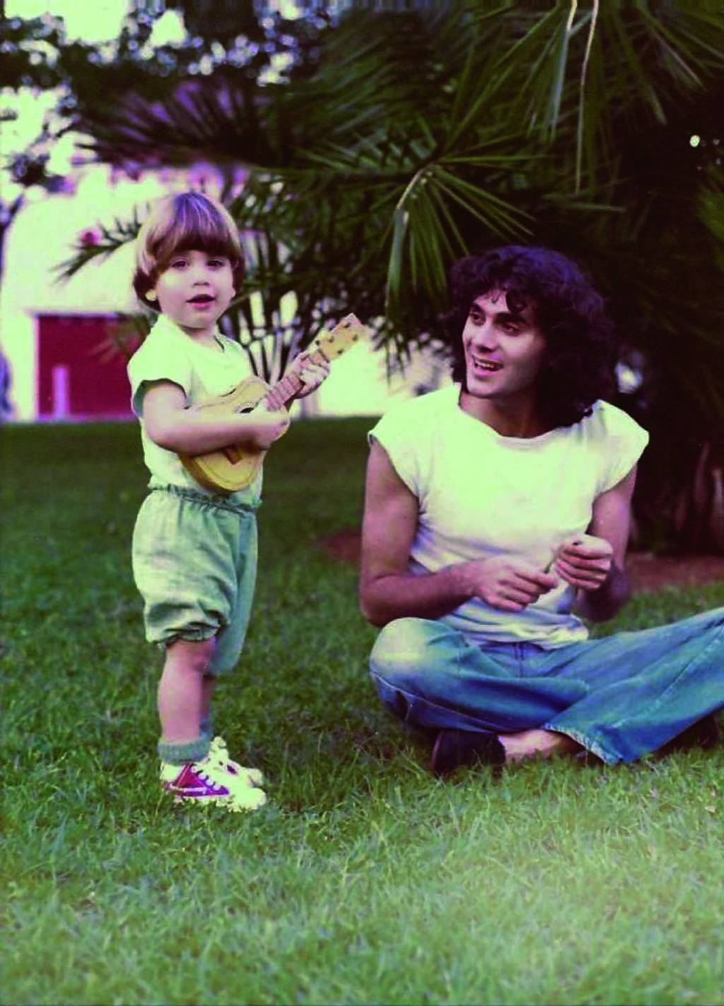 Crédito Arquivo Pessoal_Divulgação.JPG Imagem mostra pai e filho brincando na grama. A criança segura um violão de brinquedo