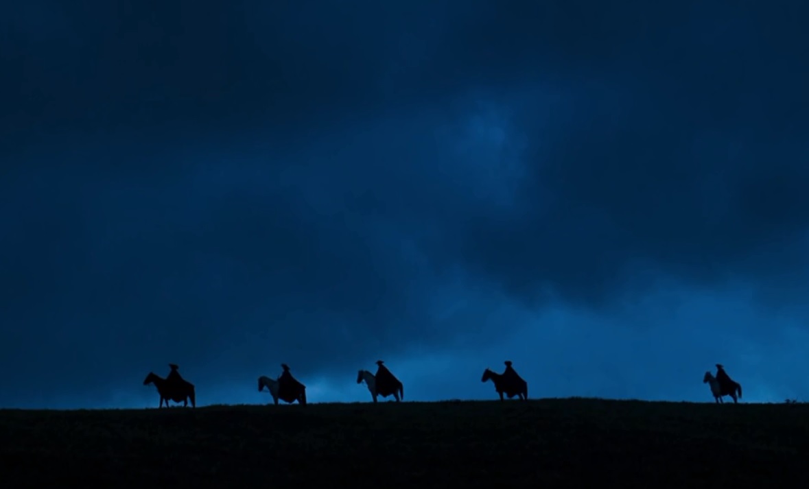 Foto ditante mostrando comitiva de homens montados emcavalo