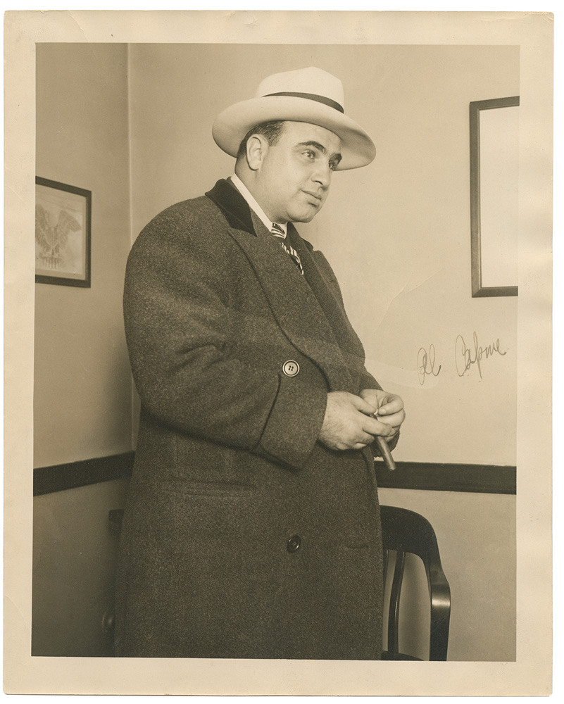 Al Capone_A Magia do Manuscrito.tif Imagem em sépia mostra homem de terno e chapéu com um charuto na ,mão