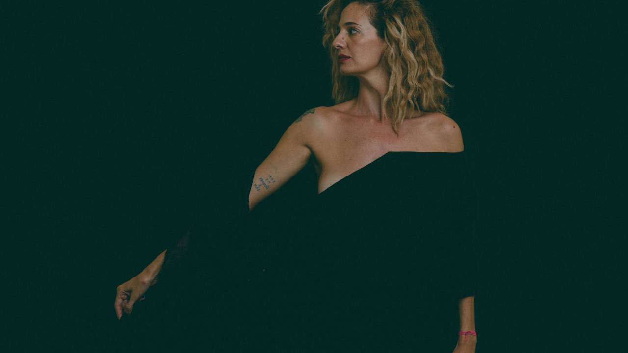 Imagem mostra mulher de perfil, vestindo roupa preta, sobre fundo preto
