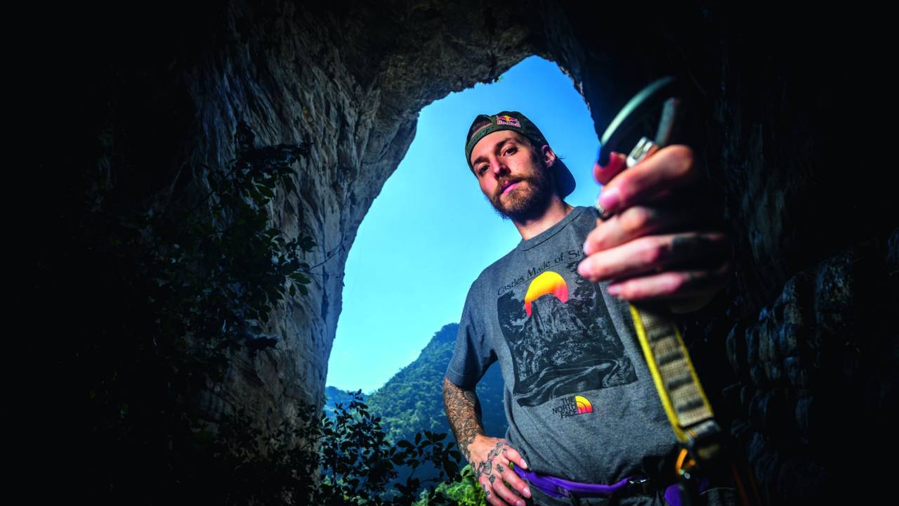 Felipe Camargo posa em caverna segurando alça de escalada.