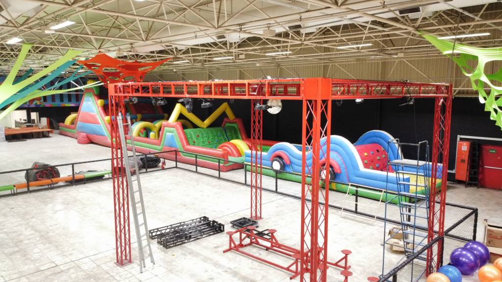 Inflavel 4 Foto de parque indoor com estruturas inacabadas e um grande brinquedo inflável e colorido ao fundo