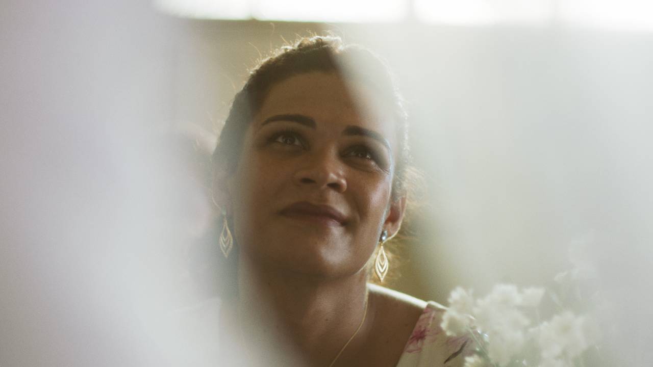 Mulher trans sorri ao olhar um vestido de noiva