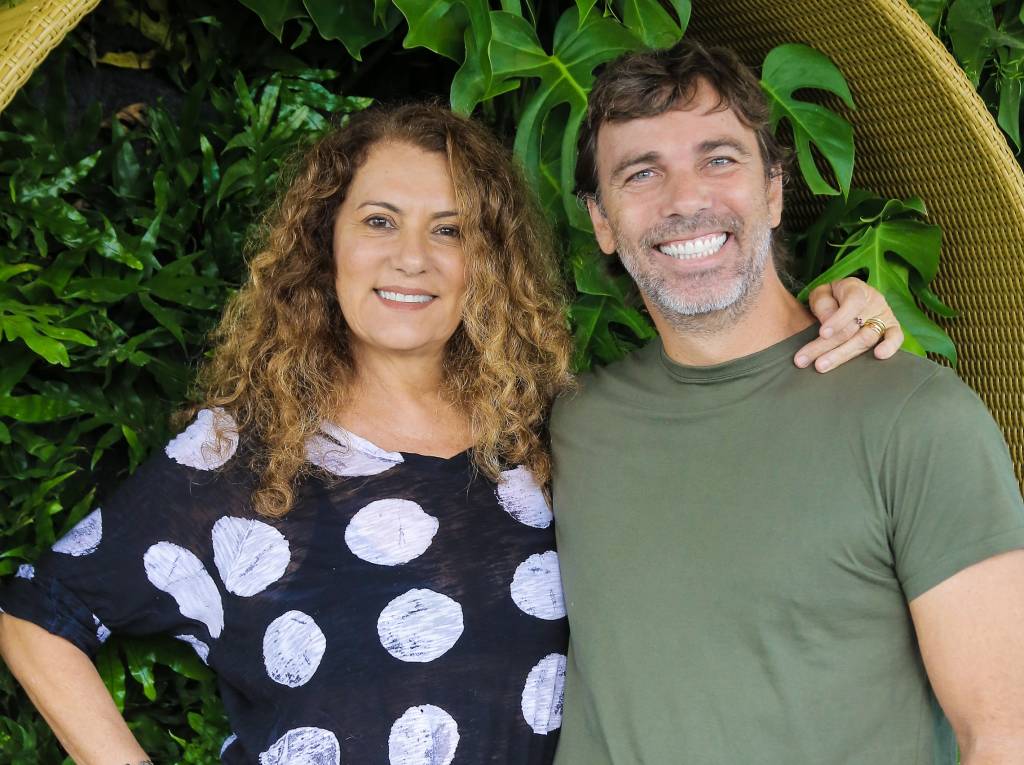 Patricya Travassos e Marcelo Faria sorriem para a câmera abraçados, ela veste camiseta preta de bolas brancas e ele camiseta básica verde.