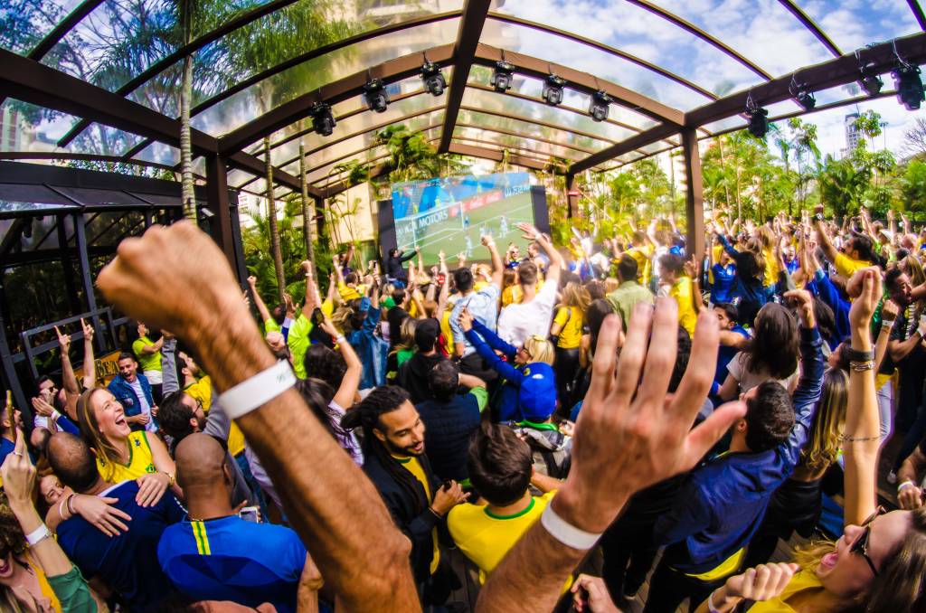 Imagem mostra pessoas com camiseta do brasil em espaço aberto