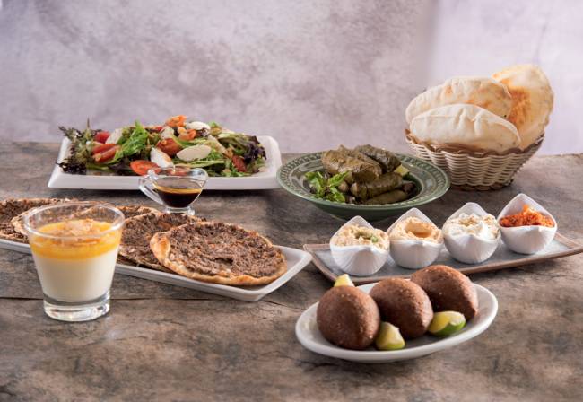 Chef Benon Quarteto de pastas do restaurante, prato com três quibes fritos recheados de carne com limões cortados em quatro ao lado, malabie com calda de damasco, salada mediterrânea e esfirra de carne