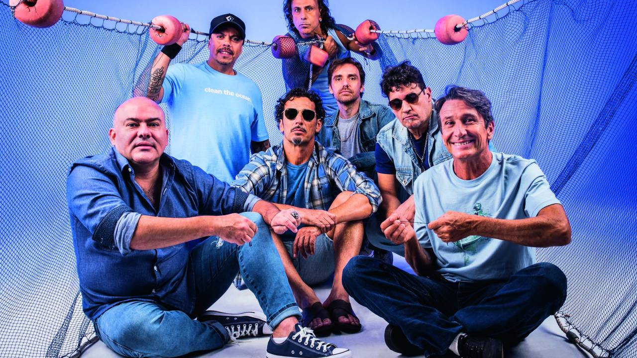 Imagem mostra sete homens de roupas azuis, segurando rede de pescador.