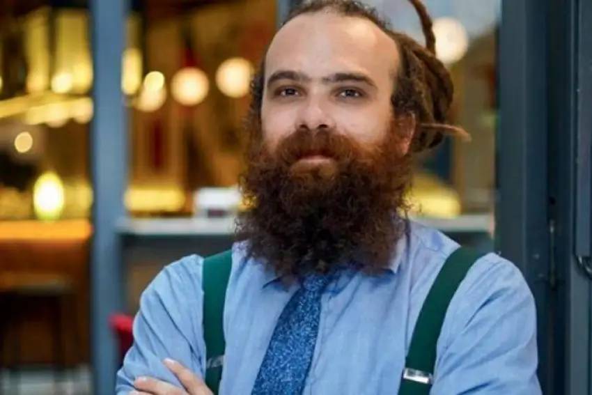 Design-sem-nome-31.jpg Imagem mostra homem barbudo com camisa azul e braços cruzados
