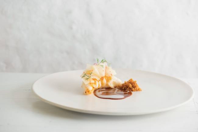 Vatapá de galinha apimentado com rocoto – Maní Prato de porcelana branca sobre mesa branca contendo Vatapá de galinha com pimenta rocoto mais salada de mamão verde e farofinha de pão frito, cabeça de camarão seco moída e amendoim tostado