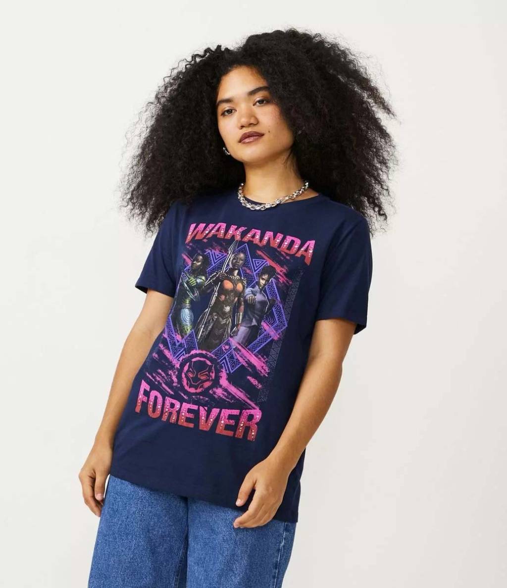 camiseta Modelo negra, magra de cabelos crespos, escuros e longos, usa camiseta com estampa das personagens femininas do filme
