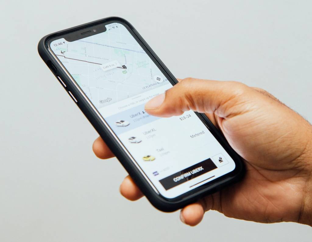 Foto de mão segurando celular com aplicativo do Uber aberto