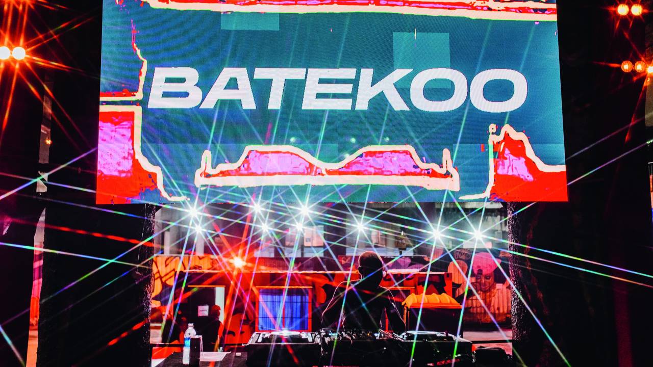 Imagem mostra DJ em ação com TV de neon ao fundo