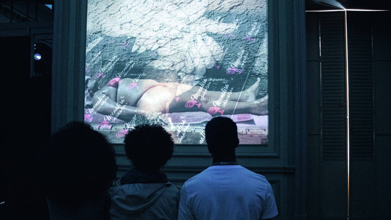 Imagem mostra pessoas em frente a projeção em parede
