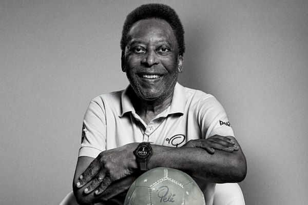 Pelé sentado com os braços sob uma bola de futebol