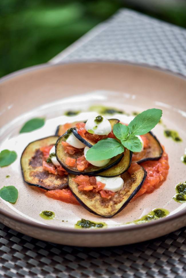 Berinjela à parmegiana com mussarela de búfala, tomate e pesto – Imma Prato de cerâmica com rodelas de berinjela com molho de tomate, mussarela de búfala e folhas de manjericão