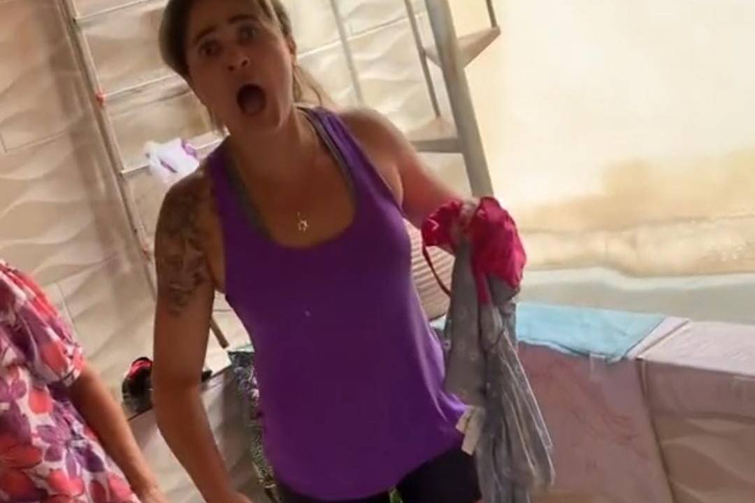 Foto de mulher de boca aberta, usando top roxo e shorts preto
