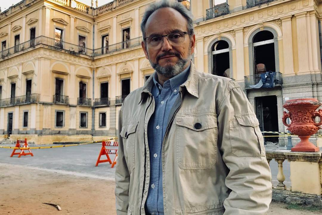 Foto de Ernesto Paglia usando óculos, jaqueta e camisa branca