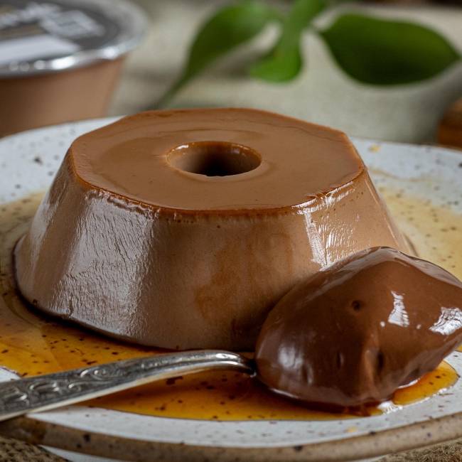 pudim chocolate – melhor pudim do mundo pudim marrom em um prato com um colher cheia do doce