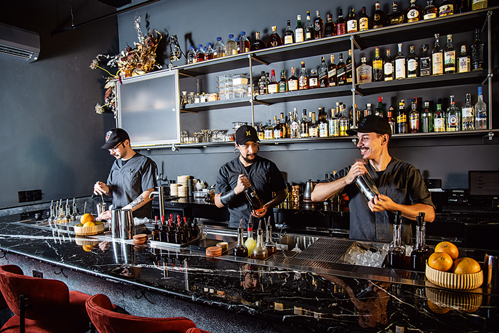 Três bartenders atrás do balcão