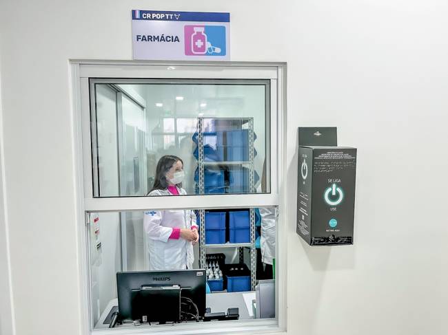 Foto mostra farmácia do Centro Janaína Lima com mulher atendente dentro da sala