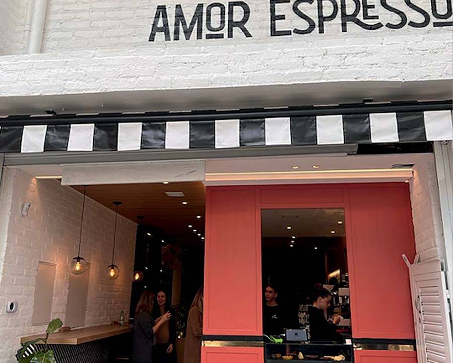 Fachada de café com parede vermelha recortada por janela e detalhes em listras pretas e brancas