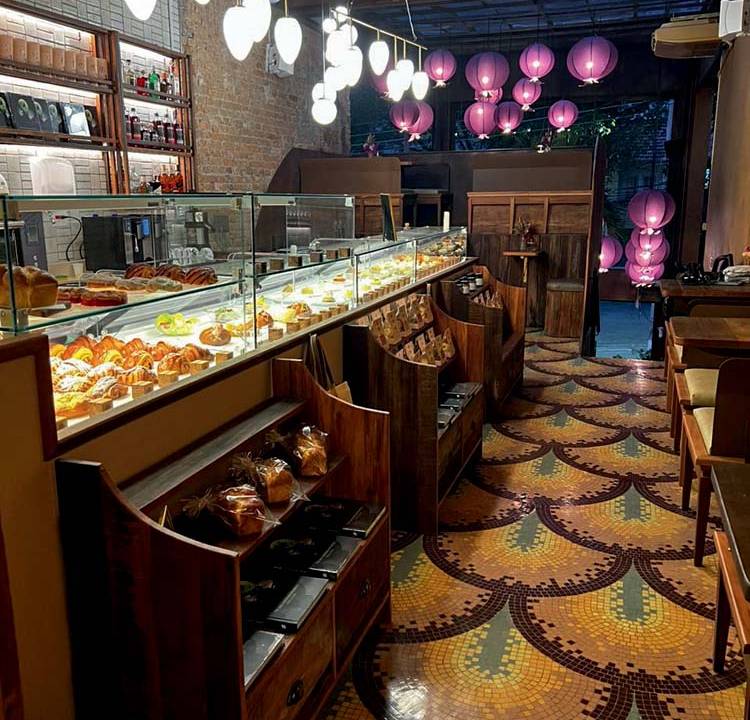 Ambiente interno com chão de mosaico de ladrilhos, balões cor-de-rosa e balcões com produtos