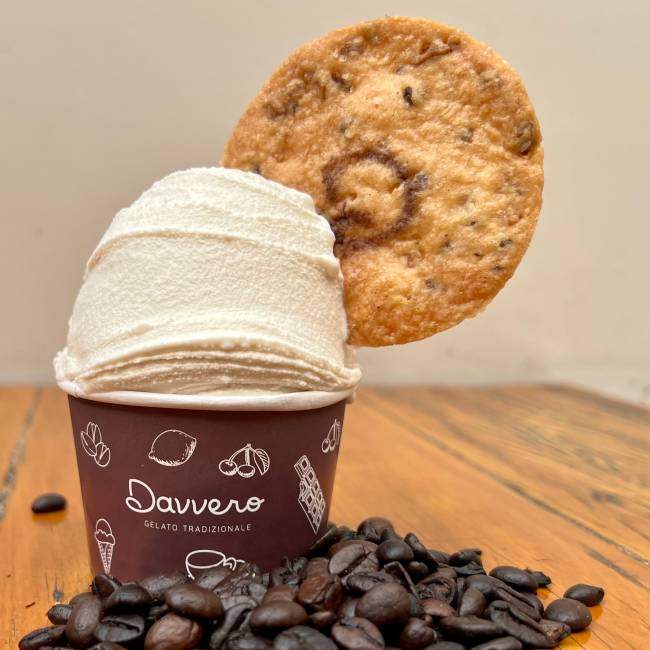 cafe bianco Davvero Potinho de sorvete com biscoito em cima e grãos de café na mesa