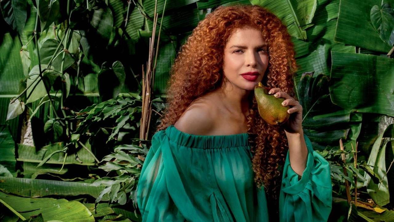 Foto mostra Vanessa da Mata, usando vestido verde, em cenário de folhas, com mangas no chão