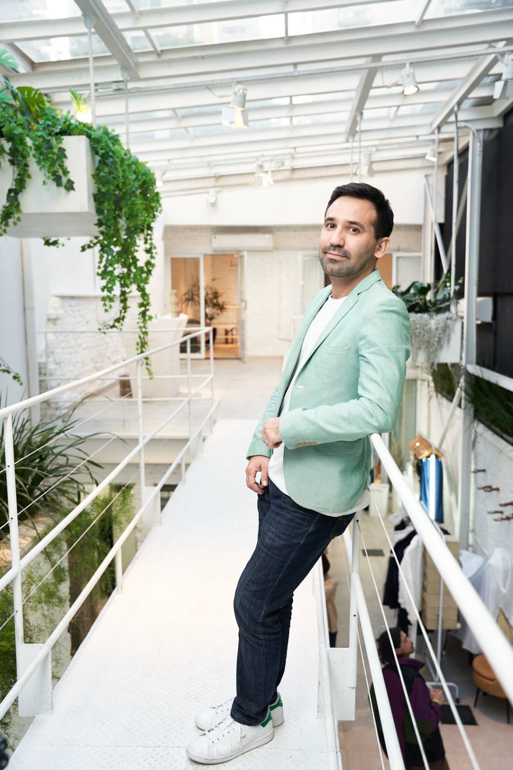 Vinicius Aguiar (Gustavo Morita) Homem branco posa apoiado em corrimão. Veste jeans com blazer azul-bebê.