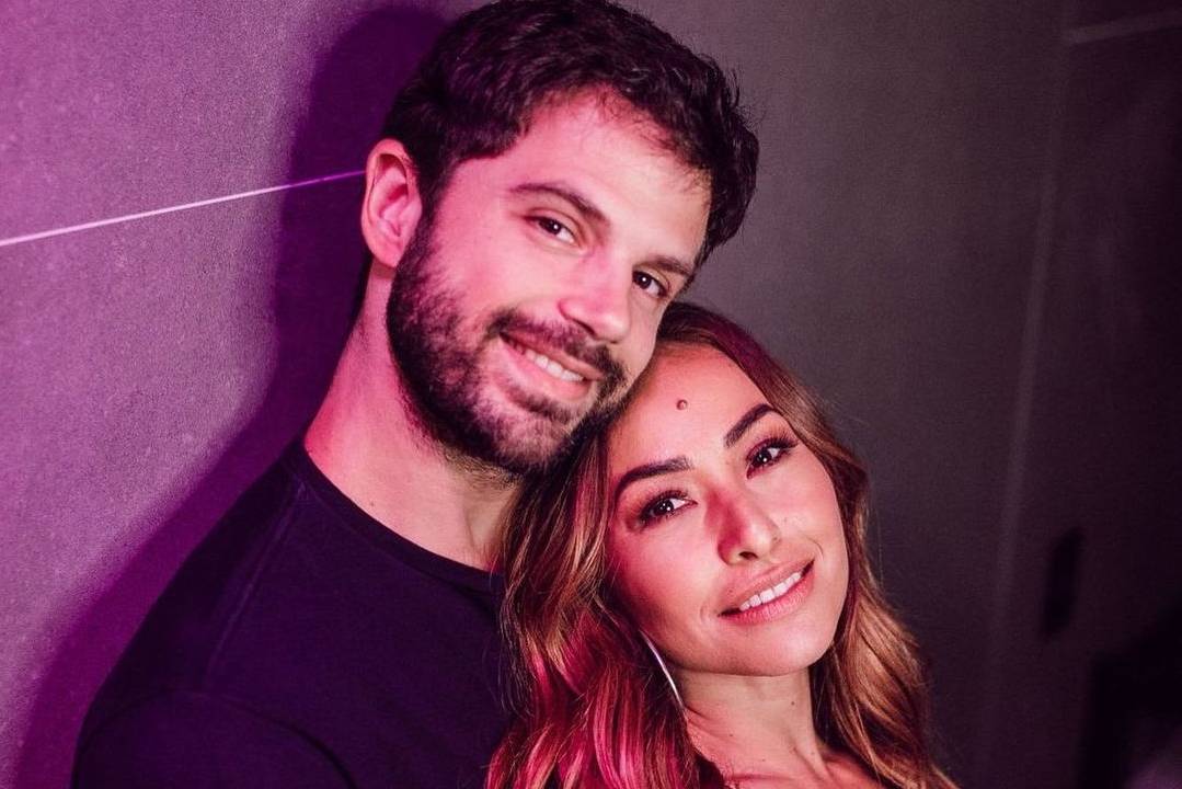 Foto de Duda Nagle e Sabrina Sato sorrindo, em fundo neutro