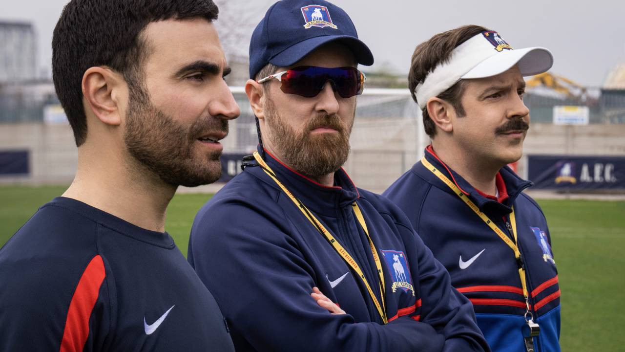 Técnicos de futebol olham sérios para um jogo no campo