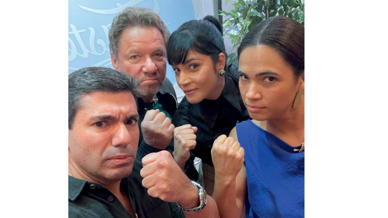 Dois homens e duas mulheres mostrando o punho fechado e de cara fechada olhando para a câmera