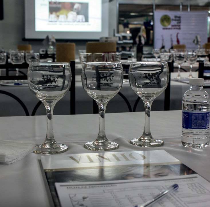 Imagem de mesa com caderneta, caneta e taças para degustação
