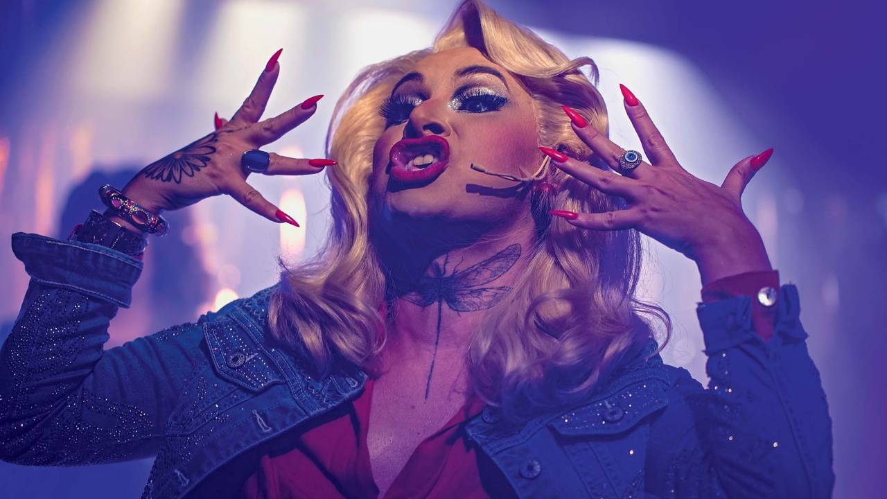 Mulher loira canta com as mãos perto da face