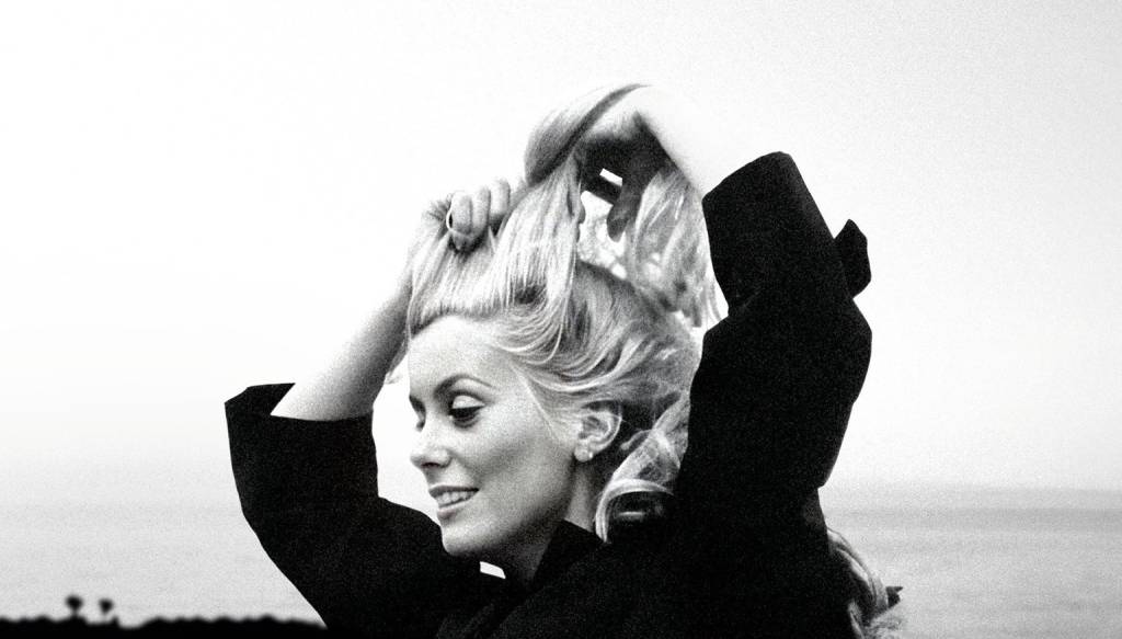 Catherine Deneuve sorrindo em foto em preto e branco