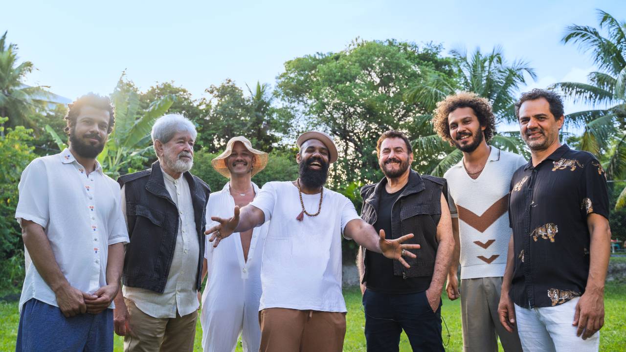 Imagem mostra sete homens sorrindo em gramado