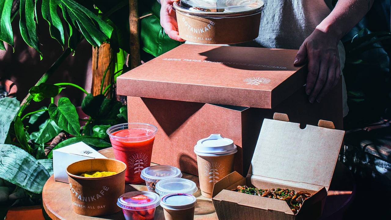 Mesa de madeira com itens de brunch em frente a caixa de madeira.