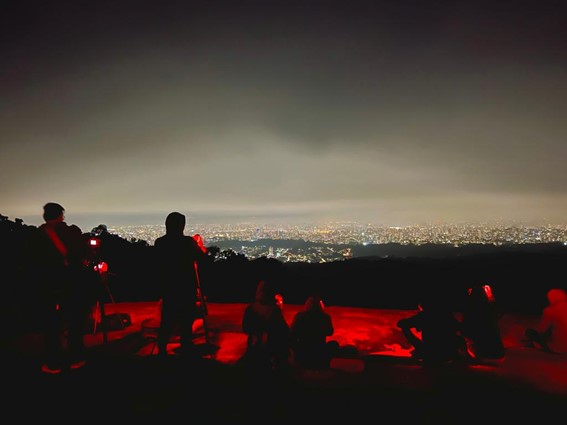 Pessoas no mirante do parque olhando a cidade à noite