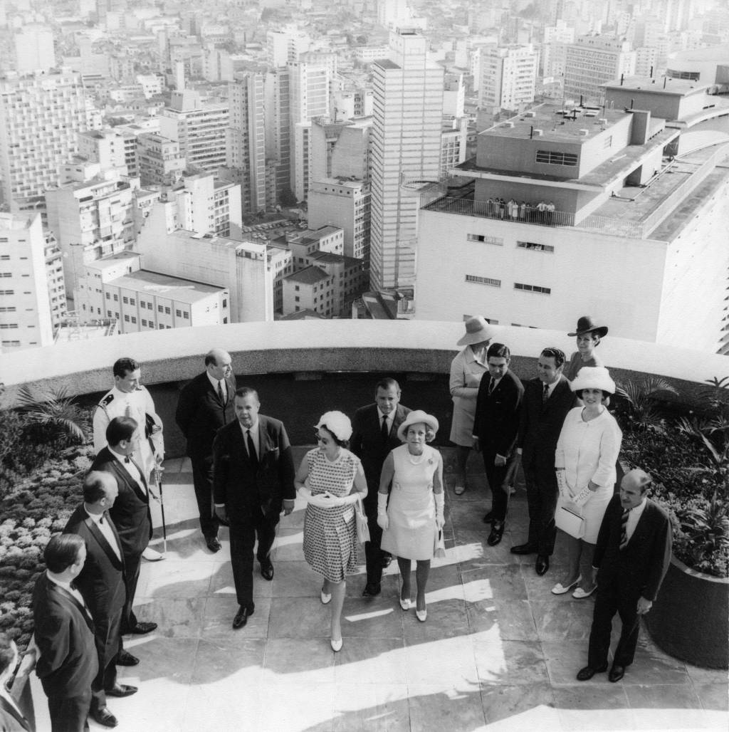 Visita da Rainha Elizabeth II_1968 Foto em preto e branco exibe terraço de edifício com presença de convidados e rainha Elizabeth II no centro.