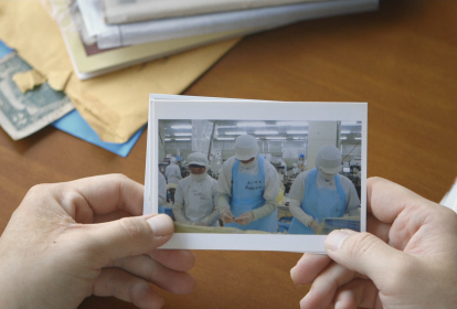 Mãos seguram uma foto de trabalhadores de uma fábrica no Japão