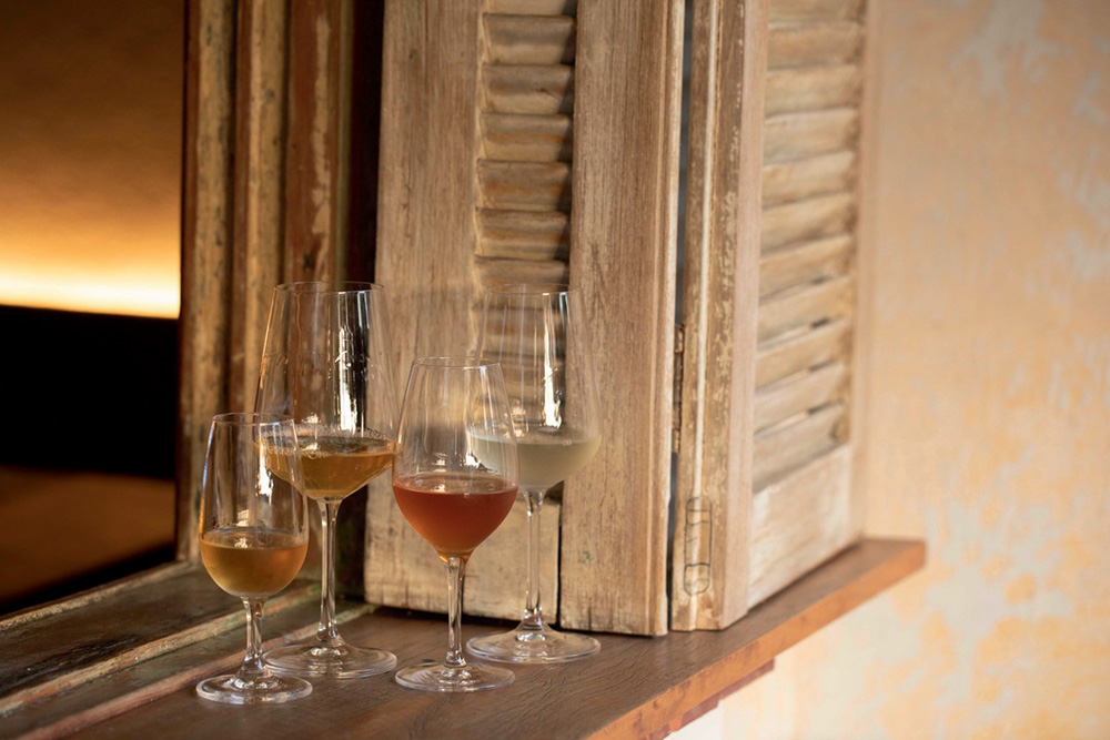 Quatro taças de vinhos variados em beiral de janela de madeira.