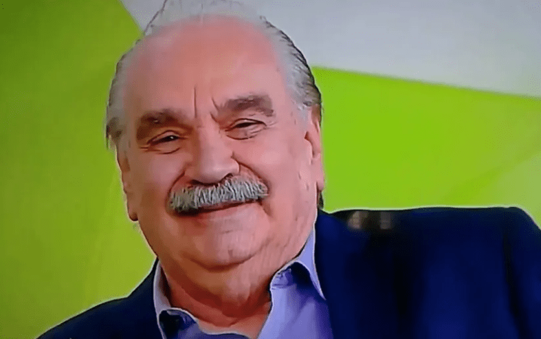 um homem de cabelos e bigode grisalhos sorrindo