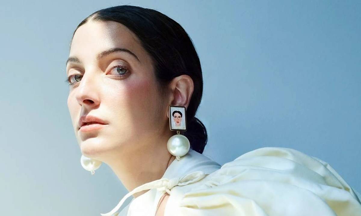 A atriz e cantora Clarice Falcão de cabelos presos um brinco grande