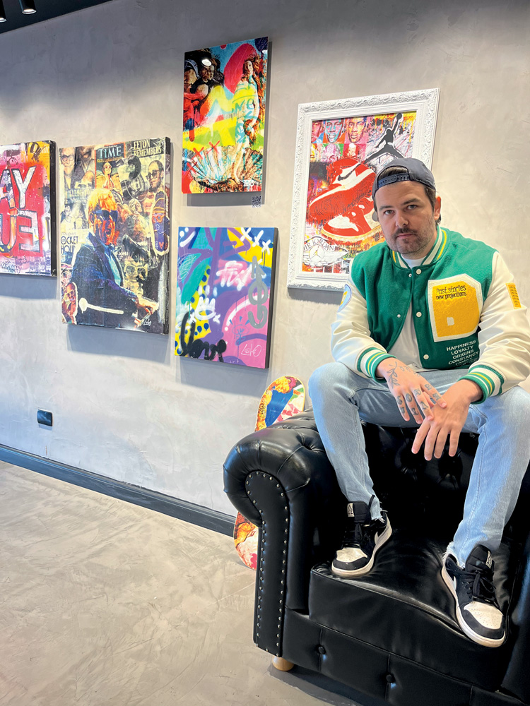 Lito (Divulgação) (1).jpeg Homem branco posa em cima de poltrona de couro preto, com quadros coloridos à sua esquerda. Veste camisa verde e branca com jeans e tênis.
