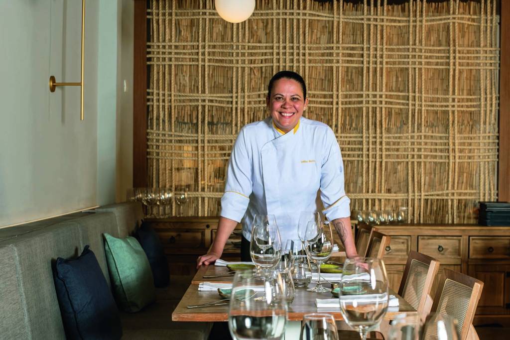 Chef de cozinha de dólmã atrás de mesa montada de restaurante.