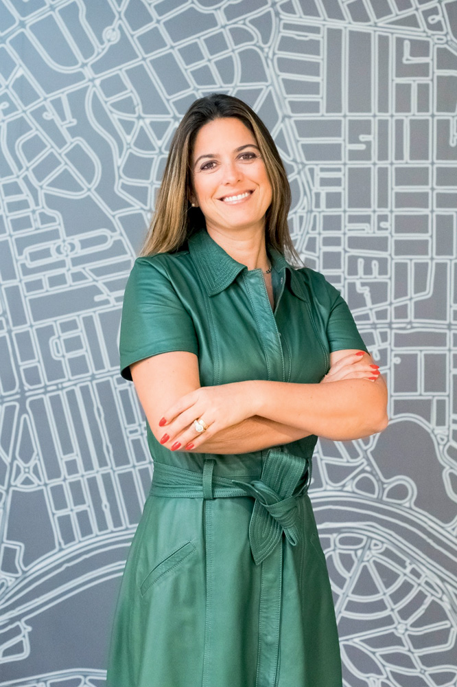 Renata Franco, CEO e fundadora app Pinguim (Ana Masotti-Divulgação).jpeg Mulher branca de cabelos lisos castanhos posa de braços cruzados em fundo com linhas brancas e fundo cinza claro. Veste vestido verde com gola e mangas curtas.