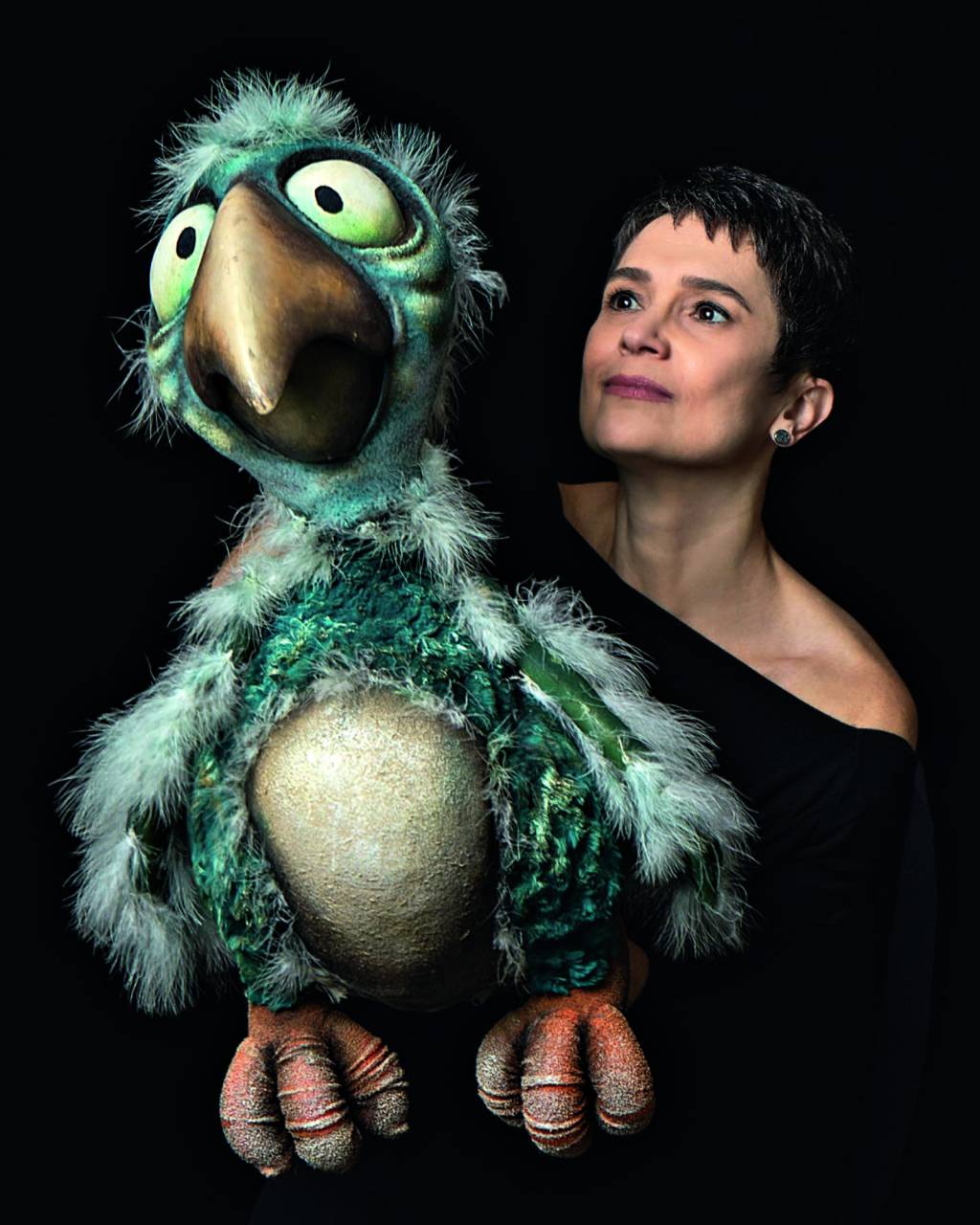 Sandra Annenberg (Fernanda Sá-Divulgação) (2).jpeg Mulher branca de cabelos pretos curtos posa segurando grande boneco de pássaro verde com barriga branca.