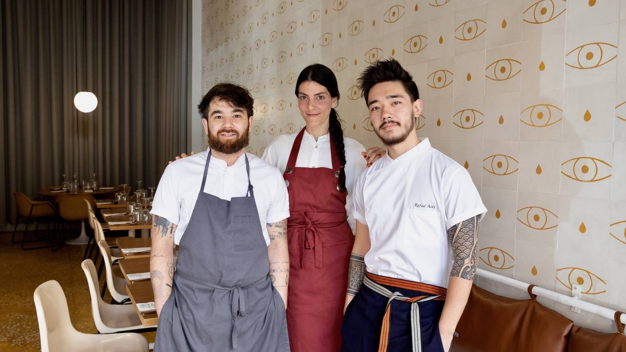 Dois homens e uma mulher ao centro com dólmãs e aventais por cima no salão do restaurante 31.