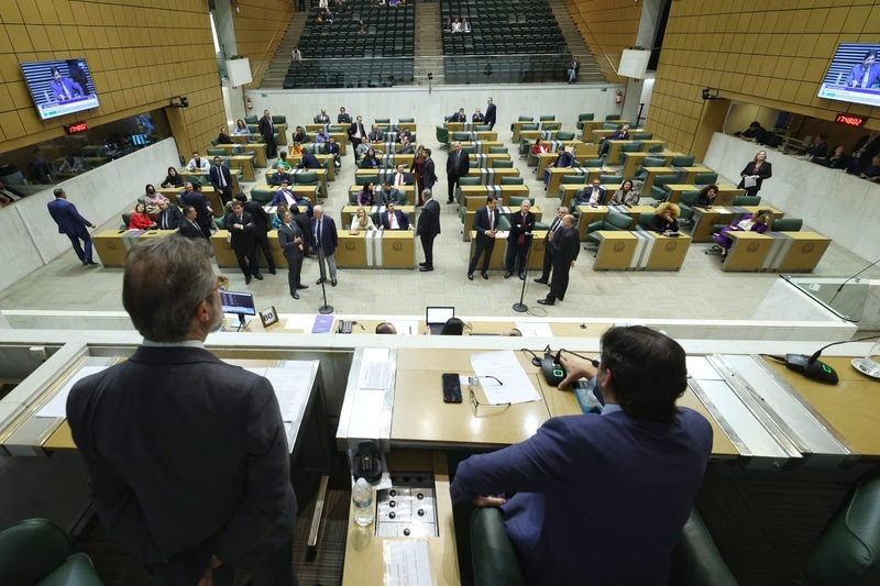 a imagem mostra a alesp por dentro, com deputados conversando e outros dois em cima de uma bancada